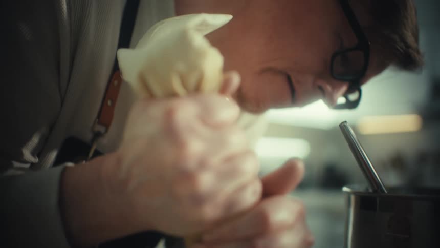 The man is making rings with batter on the pan