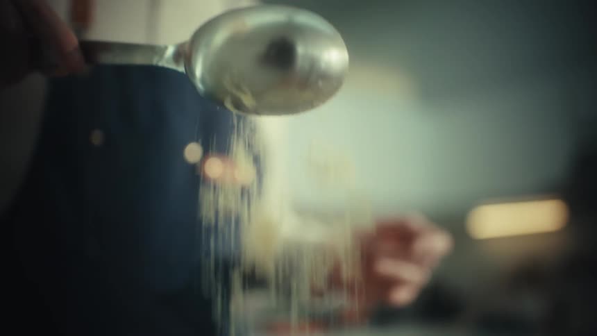 Spoon pours granulated sugar during dough preparation