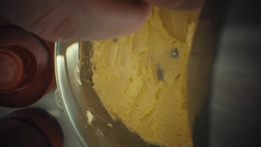 Egg is poured onto dough inside a metal bowl