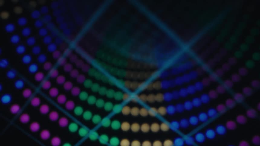 Glowing orbs of colored lights move across the darkness in a curved arched formation with the digitized lines of a grid