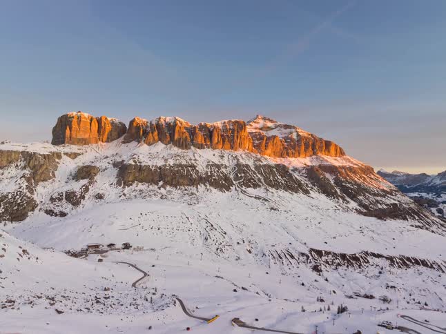 A mountain in the arctic covered in snow as the sun rises