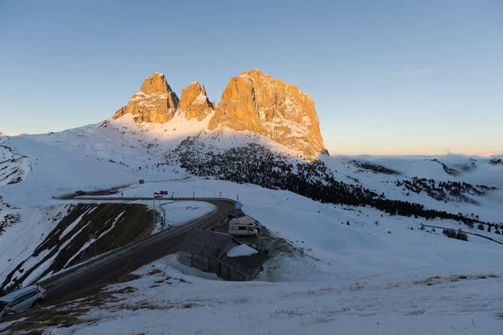 Snowcovered mountains illuminated by sunrise above a road in an alpine region