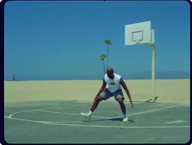 Man plays basketball on an outdoor court near the beach