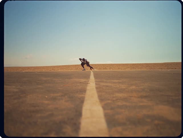 A person runs across an outdoor basketball court in a desert landscape under a clear blue sky