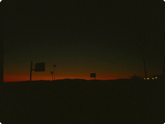 A basketball court at night with a ball thrown toward the hoop