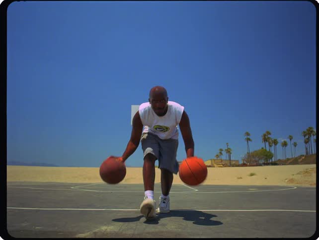 The man is dribbling two basketballs at the same time