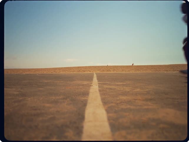 Athlete practicing a sprint start on an empty desert road under bright daylight