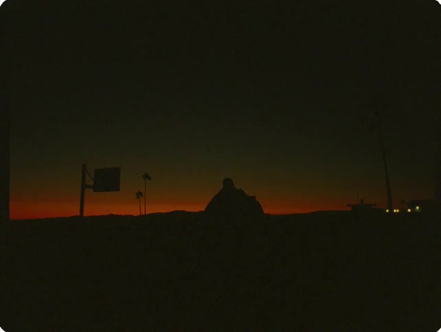 Silhouette of a person shooting a basketball on an outdoor court at dusk