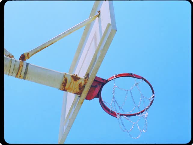 Basketball hoop with metal net seen from below against a blue sky
