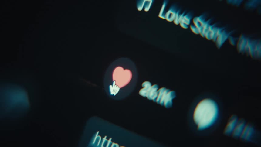 A blurred closeup of a music player interface shows a like heart and song title