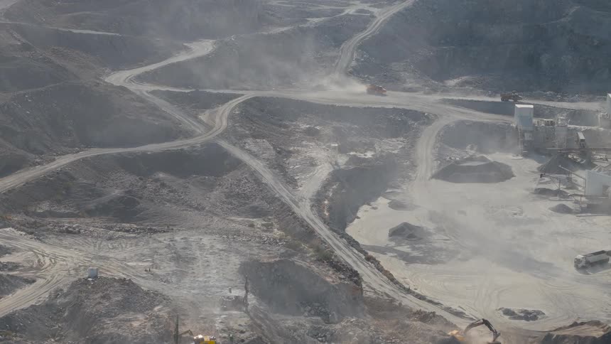 Mining area with excavators dirt roads and piles of material across an excavated landscape