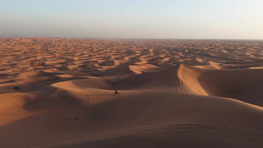 Two people riding bikes on desert sand on a sunny day