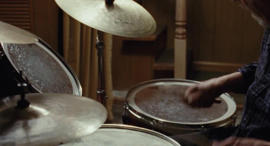 Older man plays the drums in his basement
