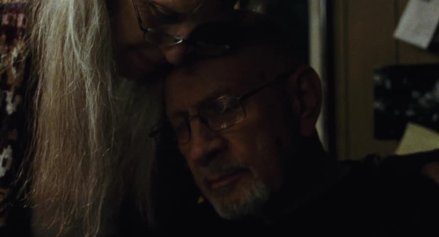 An elderly couple embrace