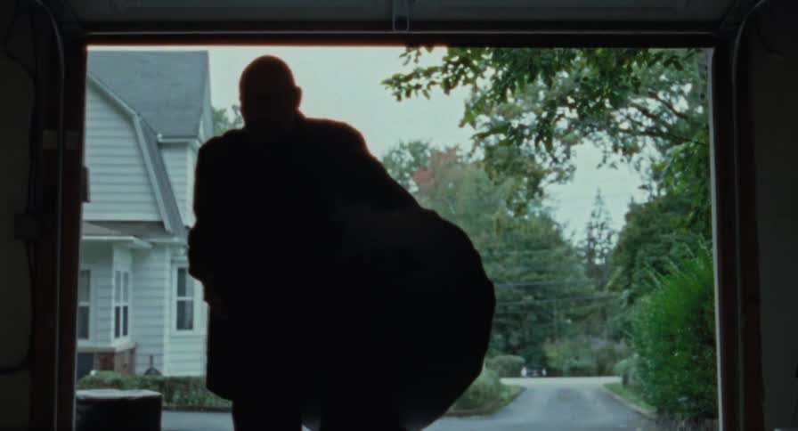 A garage door opens and an old man moves bags inside