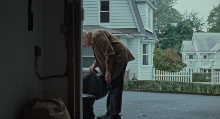 Old man moves bags into his garage