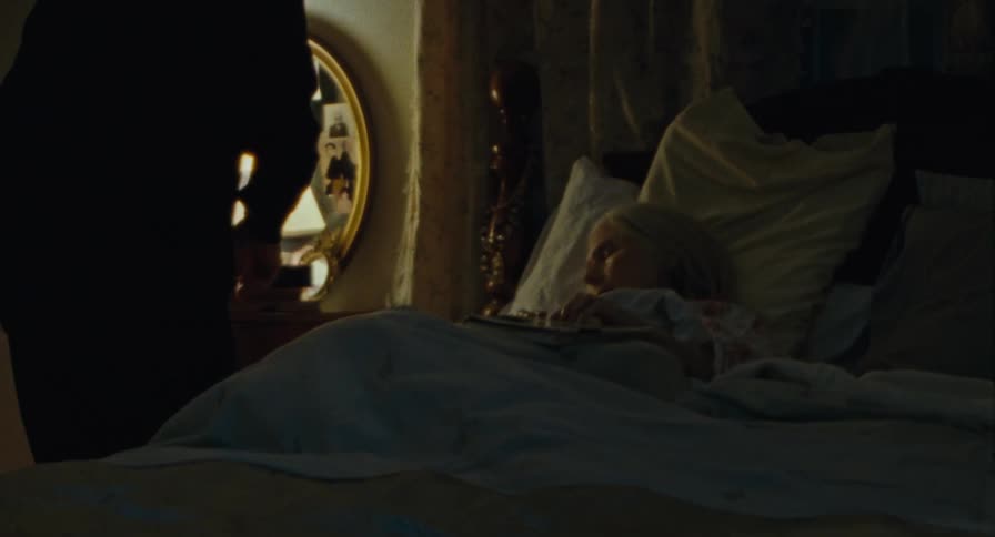 Old man takes glasses and a book off of sleeping old woman