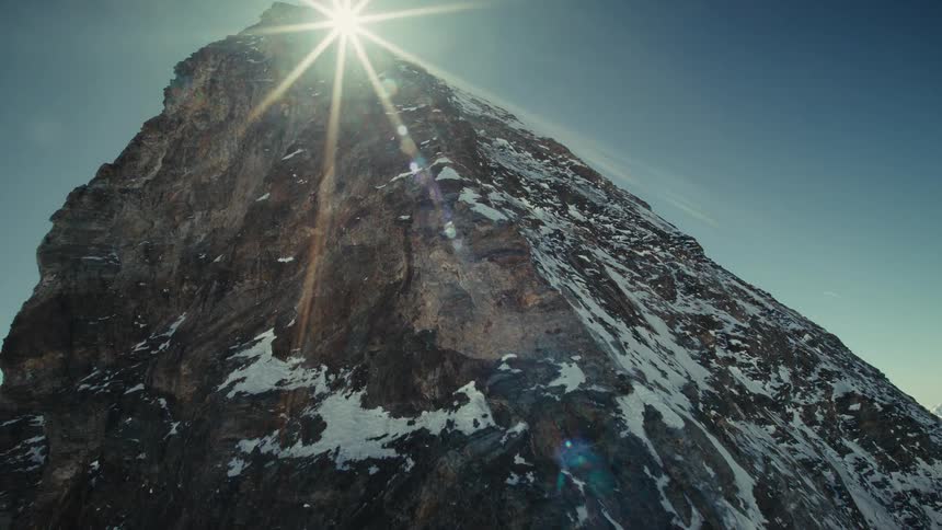 Rocky mountain face with patches of snow under a clear sky