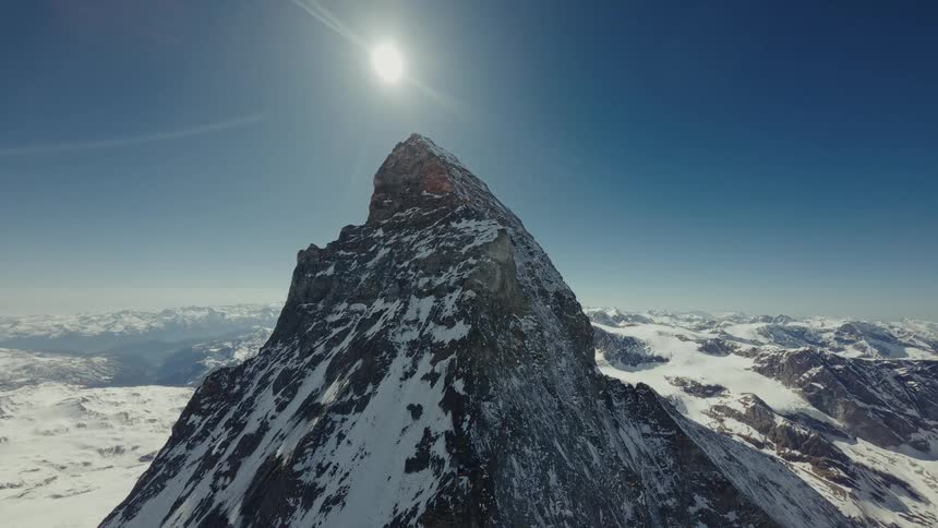Sun sits in the sky above the peak of the Swiss Matterhorn