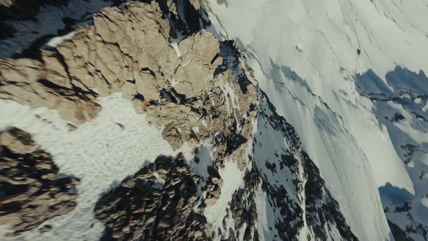 Mountain landscape with rocks and snow lit by sunlight