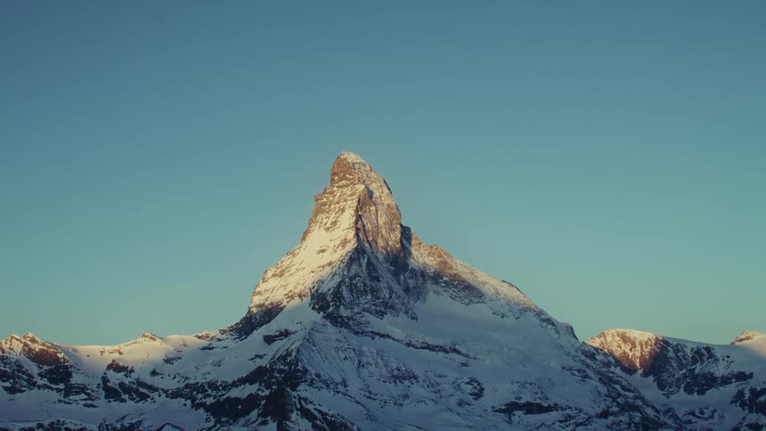 The Swiss Matterhorn rises against a clear blue sky illuminated by warm sunlight