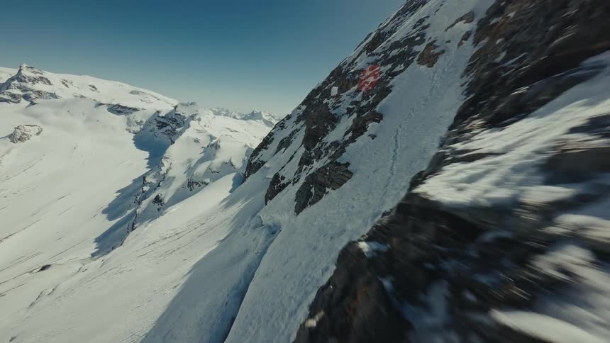 Rocky mountain slope with snow and a mountain range in the background