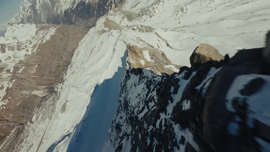 Mountain ridge with exposed rocks and snowcovered areas under blue sky