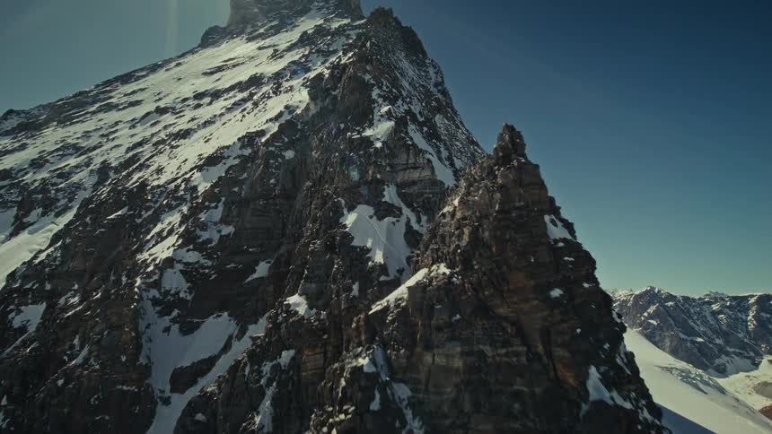 Steep snowcovered mountain peak under blue sky
