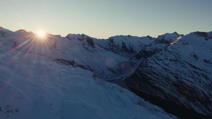 Sunlight shines over snow covered mountains with rough terrain