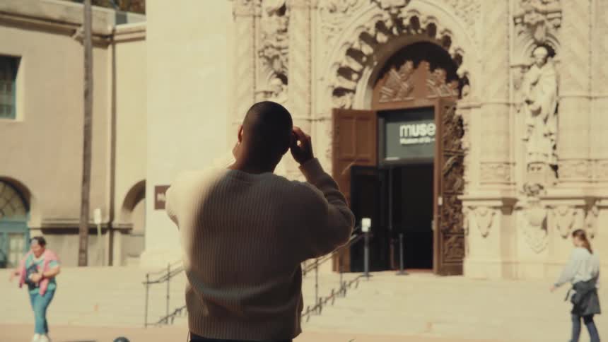 Man photographs the ornate entrance of a historic building with an open door