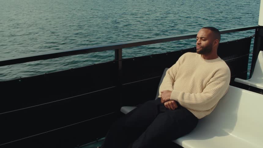 Man sitting on a boat bench looks at the sea