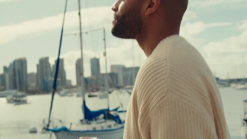 Man looks toward a marina with boats and buildings in the background