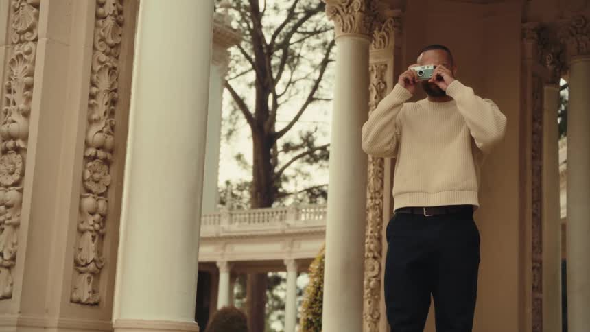 Person in light sweater photographs ornate columns at historic site