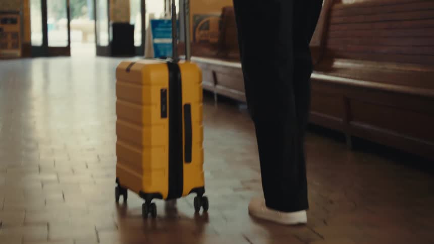 A man walking around in a building with a suitcase