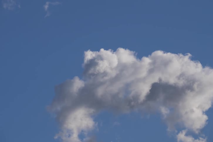 A large fluffy white cloud quickly evaporating and disappearing into a clear blue sky the timelapse captures the cloud thinning out until only a few small wisps remain before it vanishes completely