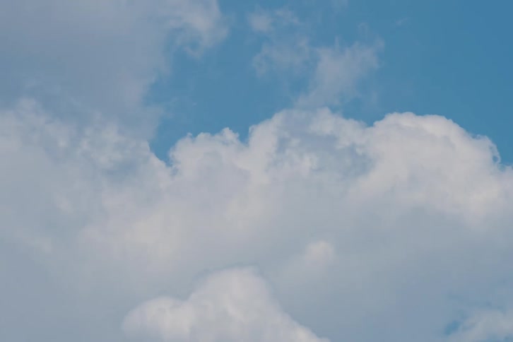 This video shows fluffy white clouds shifting and expanding across a bright blue sky the timelapse captures the gentle continuous movement of the cloud formations as they drift upward