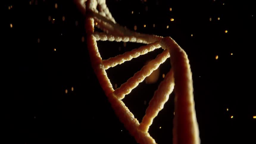 A glowing dna double helix twists against a dark background with floating particles