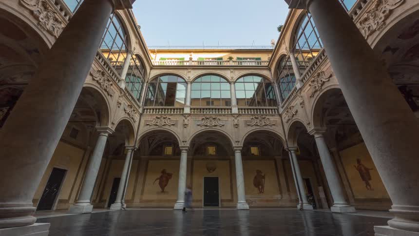 A low angle symmetrical shot of a renaissance courtyard with tall columns and arched glass windows