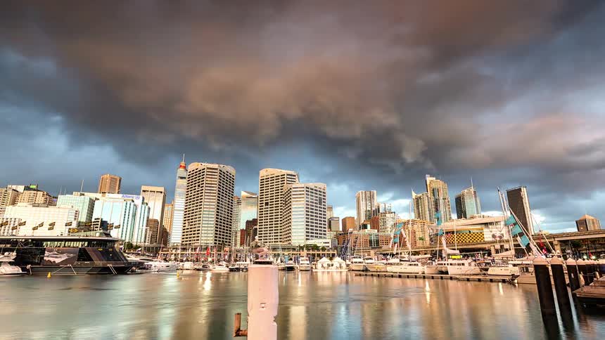 Storm clouds pass over a city marina as night falls