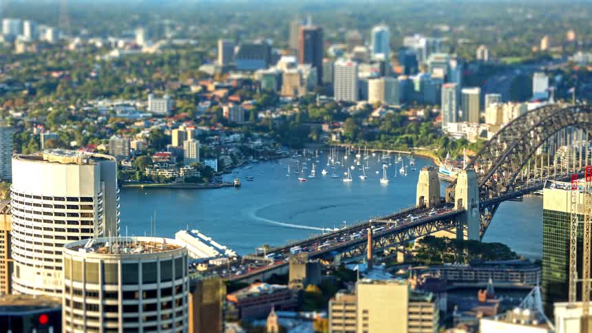 Bridge crossing a bay with anchored boats and a city skyline in the background