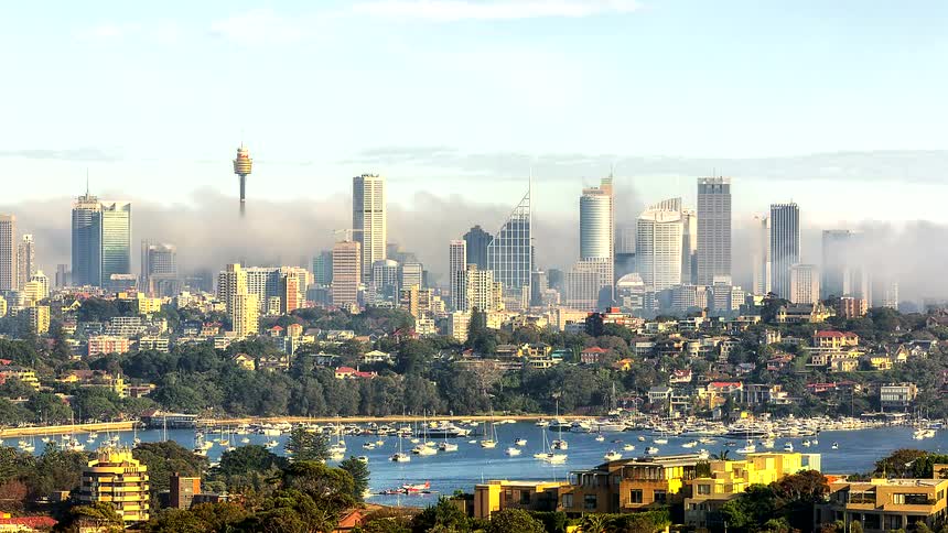 City skyline with skyscrapers in the background and boats anchored on the water in the foreground