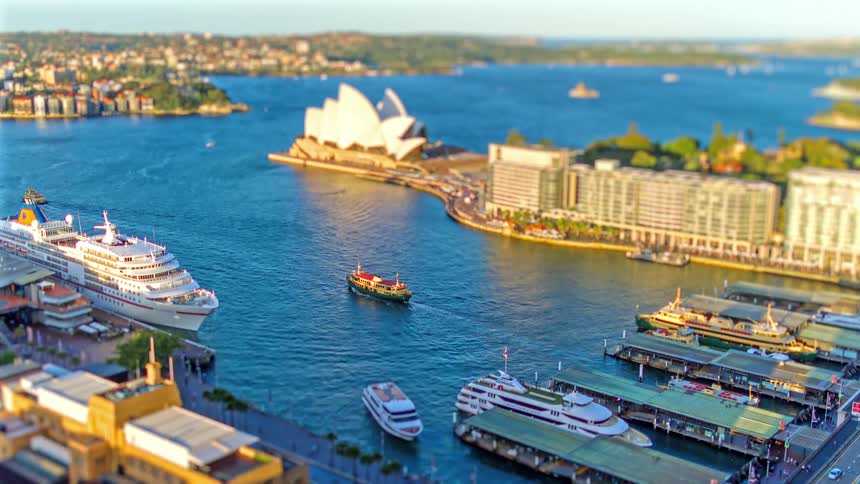 A series of boats and yachts in a harbor as some leave on a sunny day