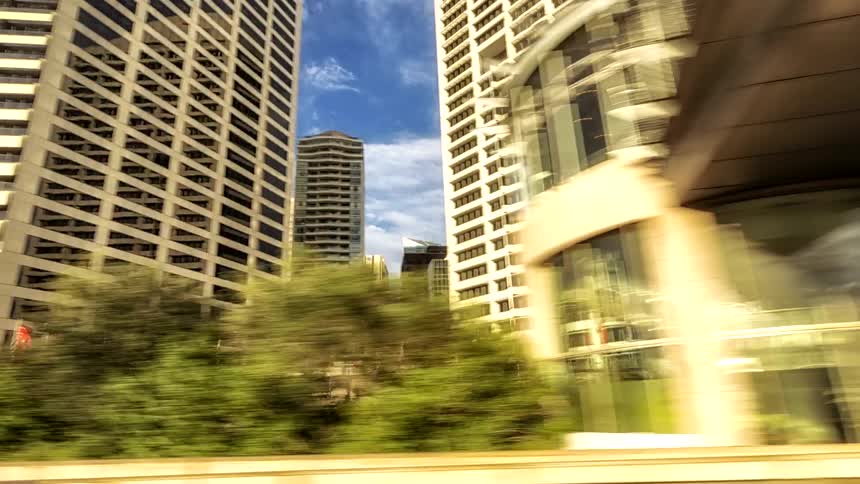 A time lapse fast video of a large city on a river with heavy traffic that travels on a bridge through a building lined street