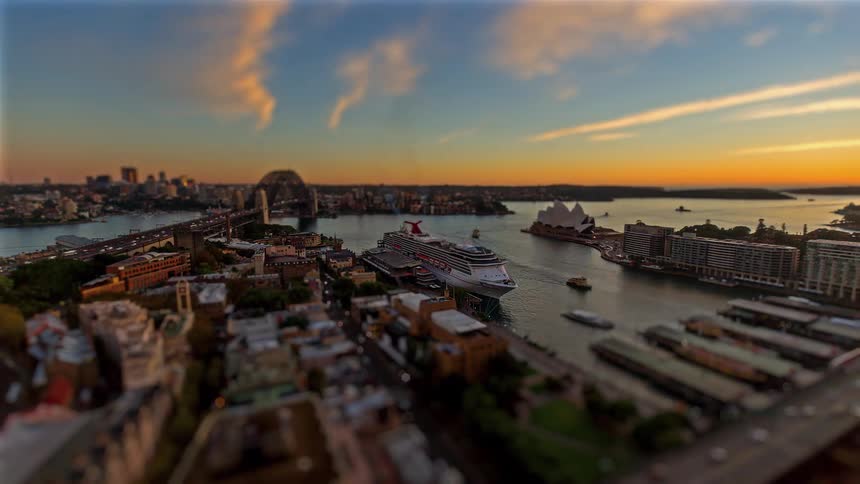 A city port with boats and ships docked in the harbor as sunset turns into night
