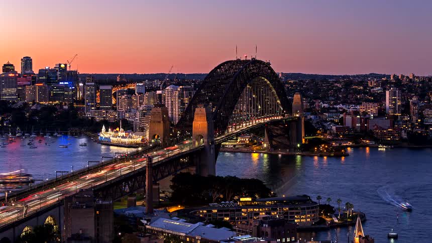 Heavy evening traffic moves across a bridge out of the city over a river