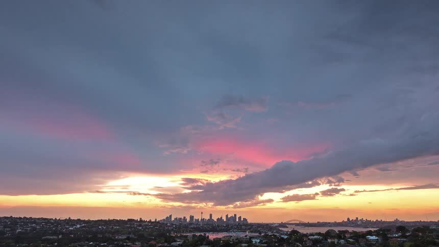 Nightfall over city with illuminated skyline under clouds