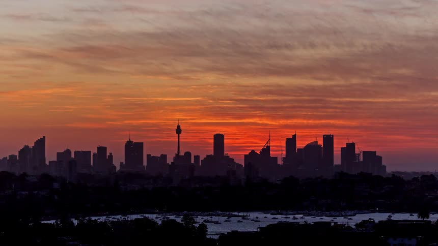 This timelapse captures a stunning sunset over the sydney skyline featuring the iconic sydney tower eye as the sun dips behind the buildingsas darkness falls the city transitions into a vibrant nightscape with office towers and streetlights illumina