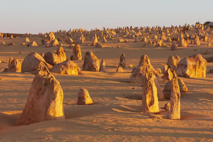 Tourists walk near rock formations in a desert