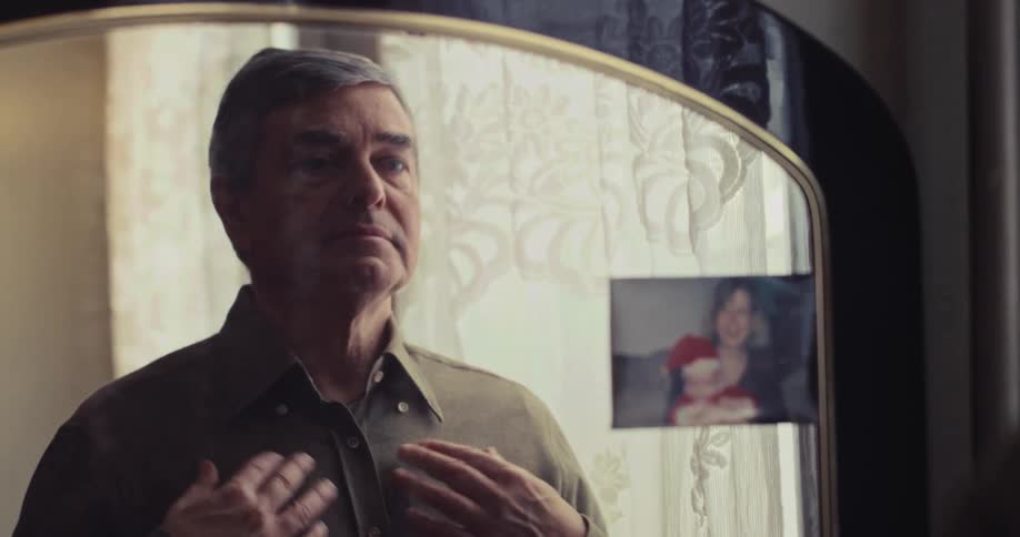 The man adjusts his shirt in the mirror