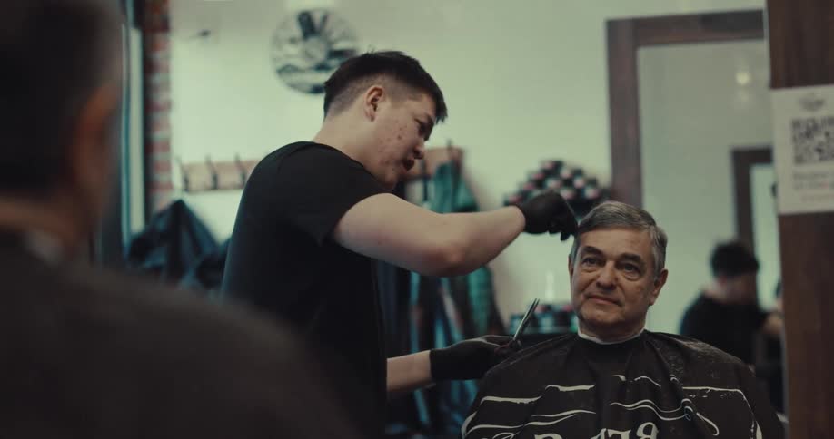 The man is having a haircut in the barbershop